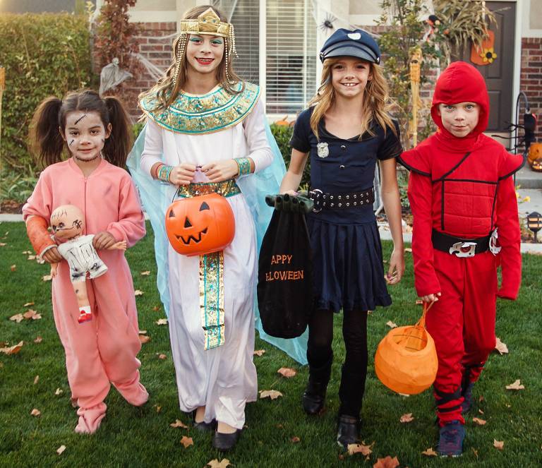 Group of kids dressed in Halloween costumes going trick or treating